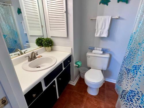 a bathroom with a toilet and a sink and a mirror at Commodore's Landing 203 - Gone Sailing, Free Activities Included! in Fort Walton Beach