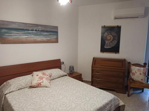 Un dormitorio con una cama y una cómoda y un cuadro. en Martino10, en Carloforte