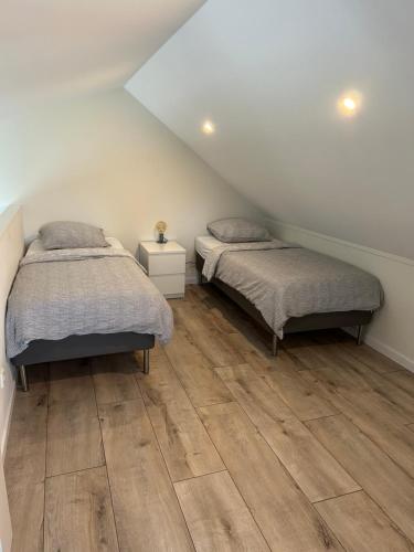two beds in a room with wooden floors at Vakantiewoning De Krab in Sint Annaland