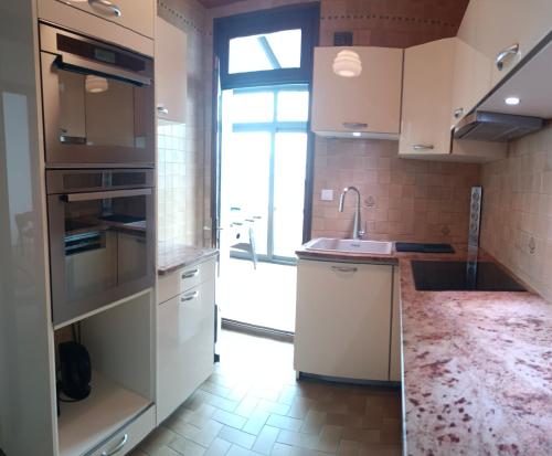 une cuisine avec des armoires blanches et un évier dans l'établissement Villa Monette -Le Crotoy, au Crotoy