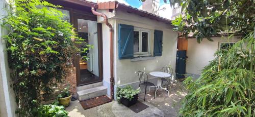 une petite maison avec une table et des chaises devant elle dans l'établissement House - Sunlit haven with outdoor terrace, garage and metro 14, RER B, à Gentilly