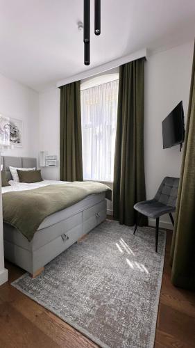 a bedroom with a bed and a chair and a window at Apartament Miła 2 Lądek-Zdrój in Lądek-Zdrój
