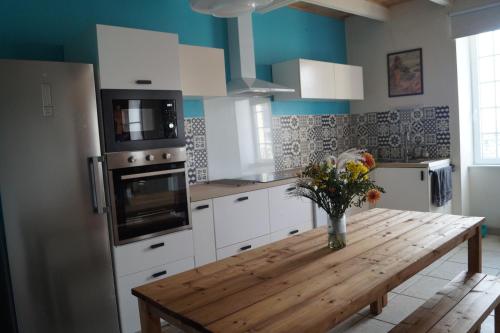 une cuisine avec une table en bois et un vase de fleurs dans l'établissement ABORD- Vue sur mer, baie de Morlaix, grande maison, école de voile à 100m, à Plougasnou