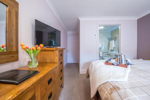 a bedroom with a dresser with a television on it at The Coach House Hotel in Pembroke