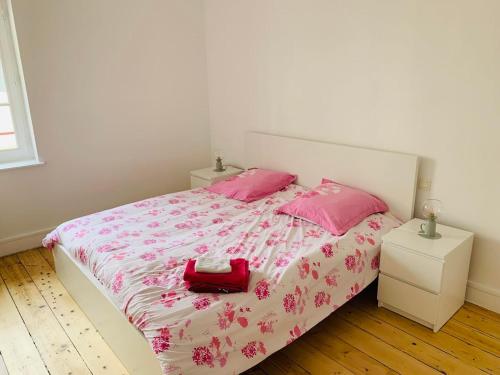 une chambre avec un lit avec des draps roses et des oreillers roses dans l'établissement Ibis Rouge, à Villars-les-Dombes