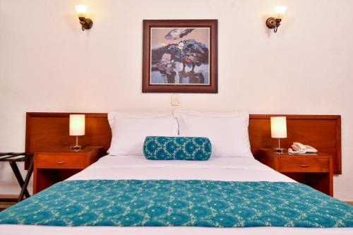 a bedroom with a bed with a green blanket at La Campana Hotel Boutique in Medellín