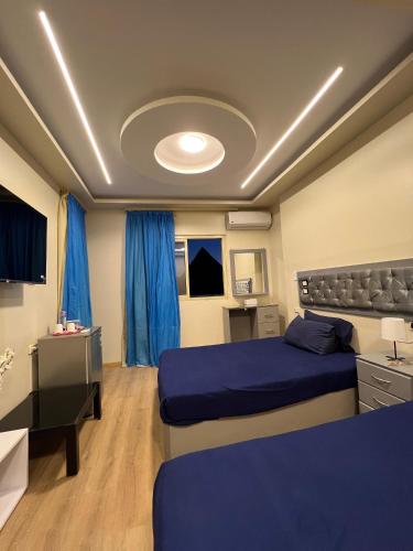 a bedroom with two beds and a desk and blue curtains at Pyramids View Inn in Cairo
