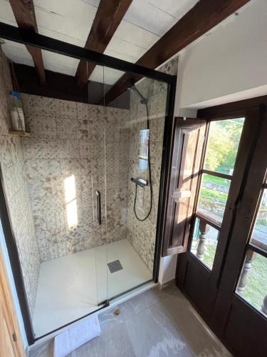 uma casa de banho com um chuveiro e uma porta de vidro em La Casina del Corral em Cangas de Onís