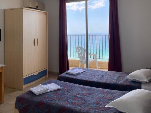 a hotel room with two beds and a view of the ocean at Hôtel A RENA D'ORU in Coggia