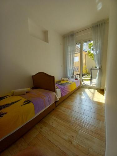 a bedroom with two beds and a sliding glass door at Apartman Gačić in Igalo