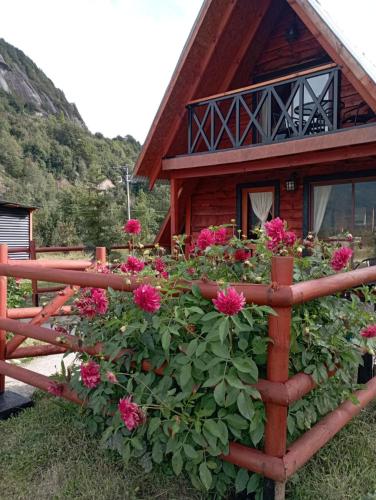 a fence with pink flowers in front of a house at CABAÑA PARCELA VISTA HERMOSA in Puerto Aisén