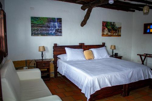 a bedroom with a white bed and a chair at Hotel Campestre Ataraxia Barichara in Barichara