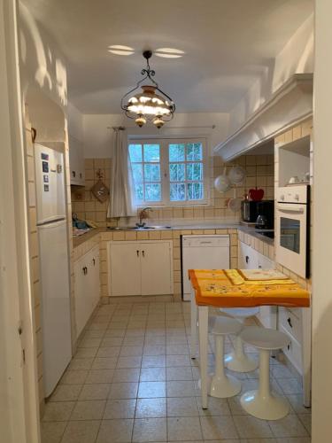 une cuisine avec des armoires blanches et une table avec des tabourets dans l'établissement Maison DE VACANCES VUE MER PROCHE PLAGE AJACCIO SANGUINAIRES REF 1070, à Ajaccio