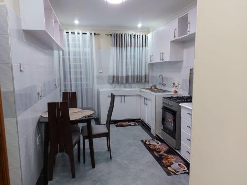 a small white kitchen with a table and chairs at JnB 2Bedroom Nakuru Naka Estate in Nakuru