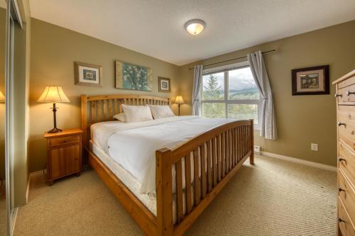 a bedroom with a wooden bed and a window at The Peaks 3 Bedroom Mountain View Condo in Radium Hot Springs