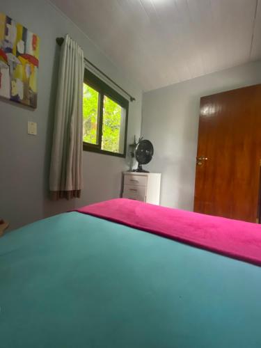 a bedroom with a bed with a pink blanket at Rancho Caiçara in São Francisco do Sul