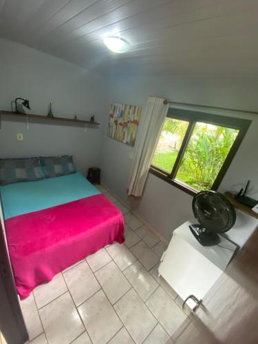 a bedroom with a red bed and a window at Rancho Caiçara in São Francisco do Sul