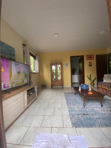 a living room with a flat screen tv and a couch at Rancho Caiçara in São Francisco do Sul