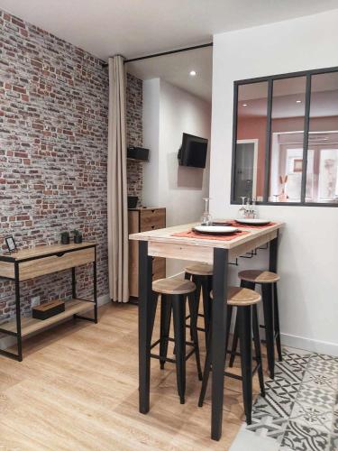 une cuisine avec une table, des tabourets et un mur en briques dans l'établissement La Cachette, à Châteauneuf-de-Galaure