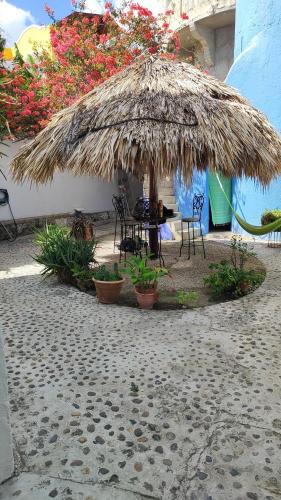 a large straw umbrella with chairs and a table in a patio at Amaranto Bed and Breakfast in Cozumel