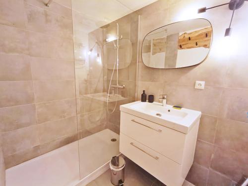 une salle de bain avec un lavabo, une douche et un miroir dans l'établissement Le nid de Juliette, T3 duplex, parking, cave, à Luchon
