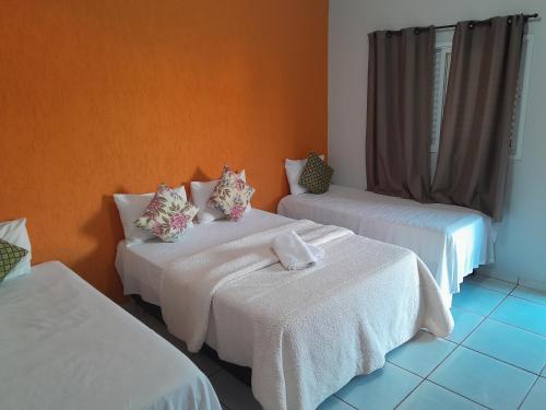 a room with two beds with white sheets at Pousada e restaurante Jardim do Cerrado MT in Nobres
