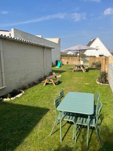 a table and chairs and a picnic table and an umbrella at La Maison - Ambleteuse - Vue sur Mer et Jardin in Ambleteuse