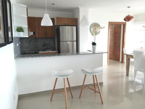 a kitchen with a counter and two white stools at Vista Marina Residence in Boca Chica