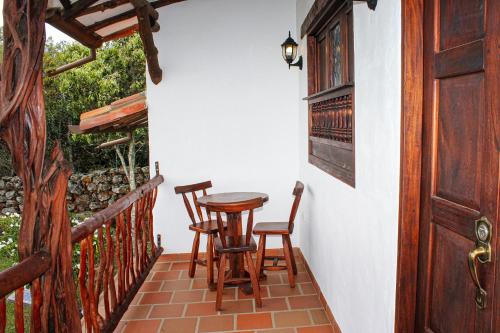 a porch with two chairs and a table and a door at Hotel Campestre Ataraxia Barichara in Barichara