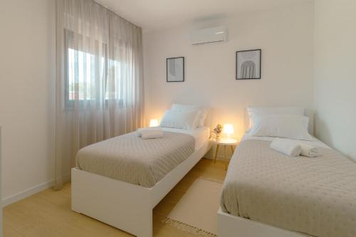 zwei Betten in einem weißen Zimmer mit Fenster in der Unterkunft Villa Pava in Zadar