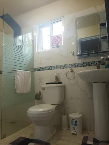 La salle de bains est pourvue de toilettes, d'un lavabo et d'une fenêtre. dans l'établissement Casa taina, à Jarabacoa