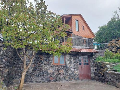 a stone house with a red door and a tree at Edis Dacha in Tsalka