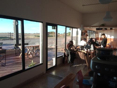 un gruppo di persone seduti ai tavoli in una stanza con finestre di Don Enrique Bar&Hostel a San Gregorio