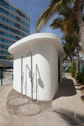 a white building with a sign on it next to a palm tree at Marítima Golf Apartment Steps from the Beach in Bucerías