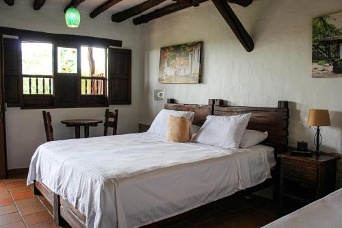 a bedroom with a bed with white sheets and windows at Hotel Campestre Ataraxia Barichara in Barichara