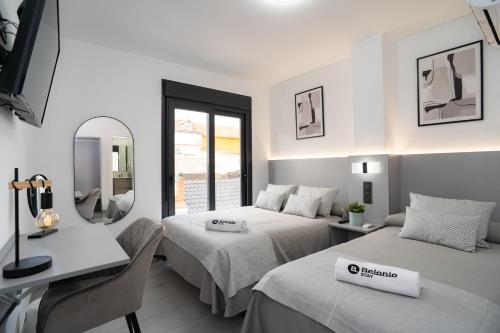 1 dormitorio con 2 camas, escritorio y espejo en Stay Belonio, en Málaga