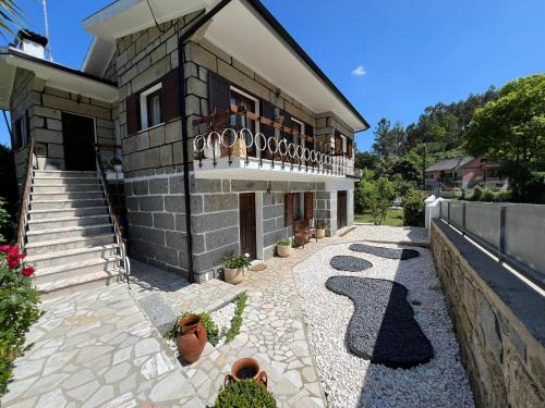 Una casa con un balcón con plantas en macetas en un patio. en VILA GUIA in Valdreu, en Braga