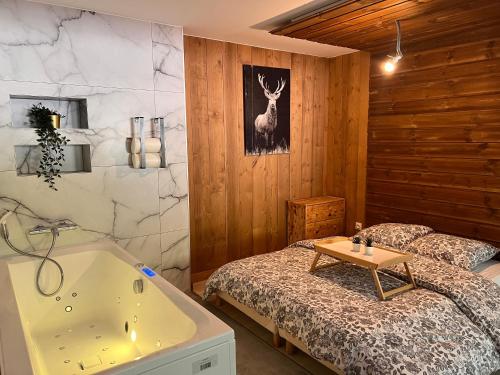 une chambre avec un lit et une baignoire et un lit avec un cache-sommier dans l'établissement Hohneck - Studio de Montagne La Bresse / Gerardmer, à La Bresse