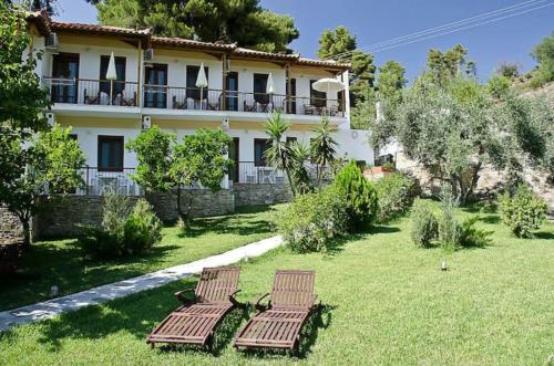 a house with two chairs in a yard at The Pine Trees in Agnontas