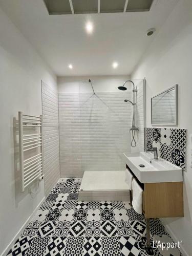 La salle de bains est pourvue de carrelage noir et blanc et d'un lavabo. dans l'établissement L' Appart' , tendance et épuré avec bel extérieur, proche du centre, à Amiens