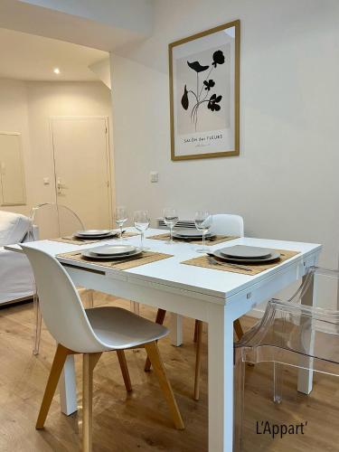 - une table à manger blanche avec des chaises et des verres à vin dans l'établissement L' Appart' , tendance et épuré avec bel extérieur, proche du centre, à Amiens