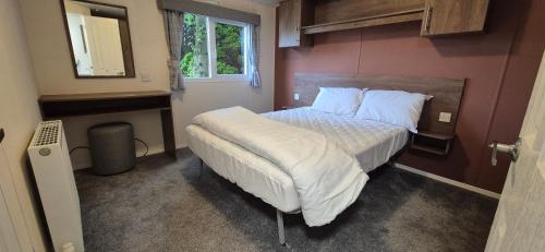 a bedroom with a bed with white sheets and a mirror at Excellent Static Caravan in Shanklin