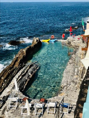 a pool of water with chairs and boats in the ocean at Angolo Di Mare in Genova