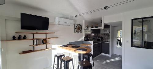 Il comprend une cuisine avec une table et une télévision murale. dans l'établissement Une pépite au calme, vue mer, port, Piscine, au Cap d'Agde