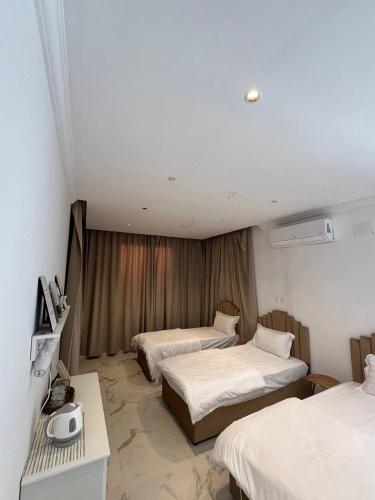 a hotel room with three beds and a desk at فيلا اورنيلا in Al Hada