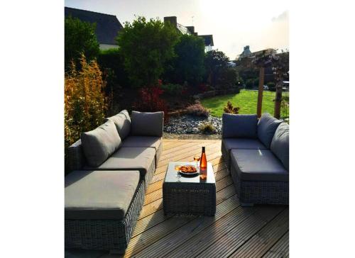 a patio with couches and a table on a deck at Maison Les Agapanthes. in Lanmodez