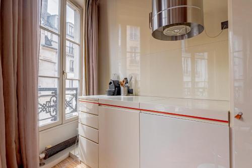 une cuisine avec des armoires blanches et une fenêtre dans l'établissement Love Nest Jardin du Luxembourg, à Paris