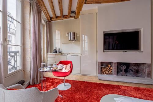 un salon avec une chaise rouge et une cheminée dans l'établissement Love Nest Jardin du Luxembourg, à Paris
