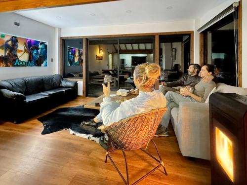 eine Gruppe von Menschen, die in einem Wohnzimmer sitzen und ein Videospiel spielen in der Unterkunft Orilla de Lago con Hot Tub, parrilla y vistas in Puyehue