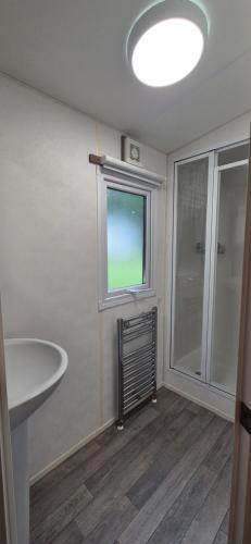 a bathroom with a sink and a window and a shower at Excellent Static Caravan in Shanklin